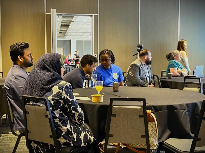 A group of graduate students sits at a table, preparing to present their publicly engaged research.